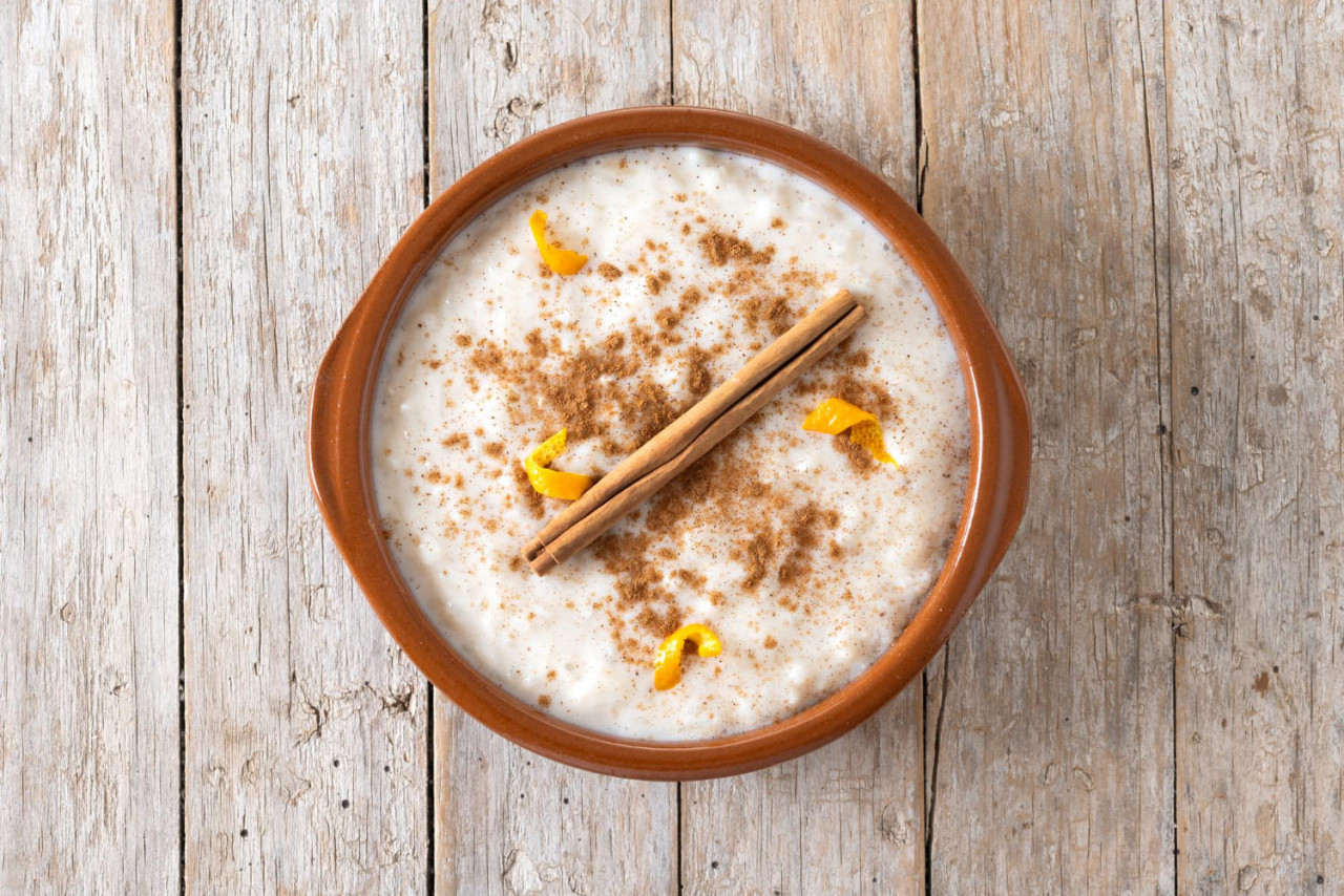 arroz con leche arroz doce com canela em tigela de barro na mesa de madeira