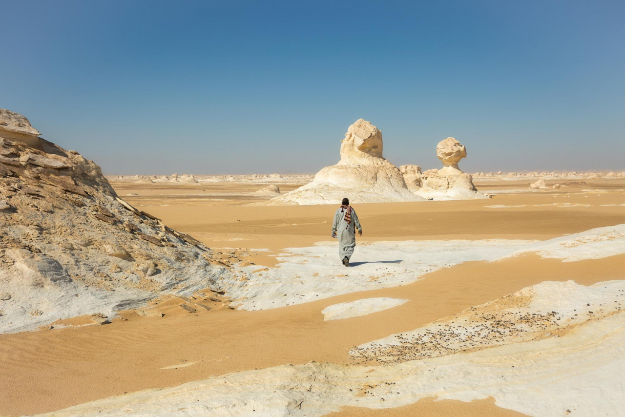an egyptian walks through the black and white desert in egypt bahariya