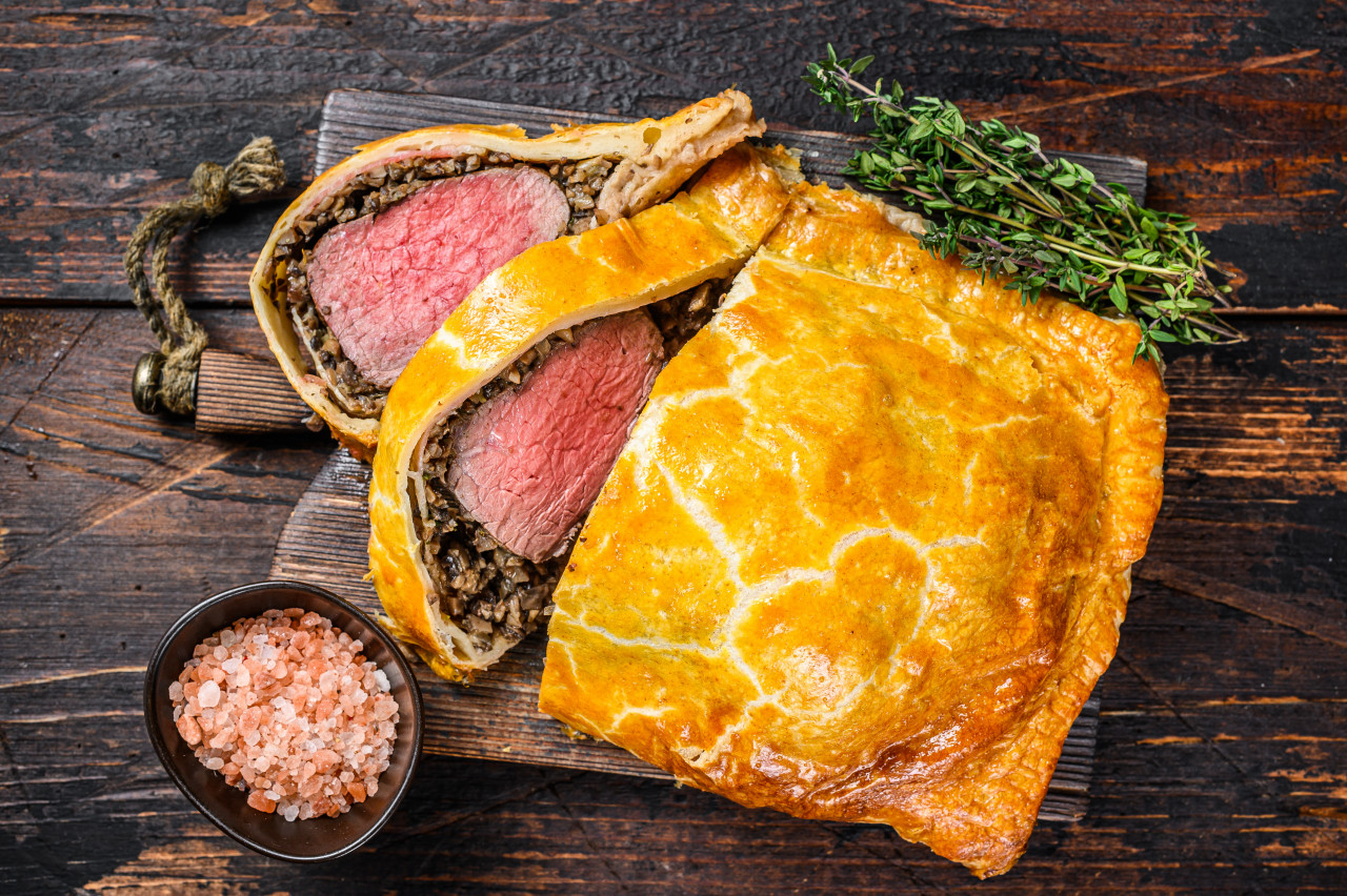 homemade beef wellington puff pie with tenderloin meat cutting board dark wooden background top view