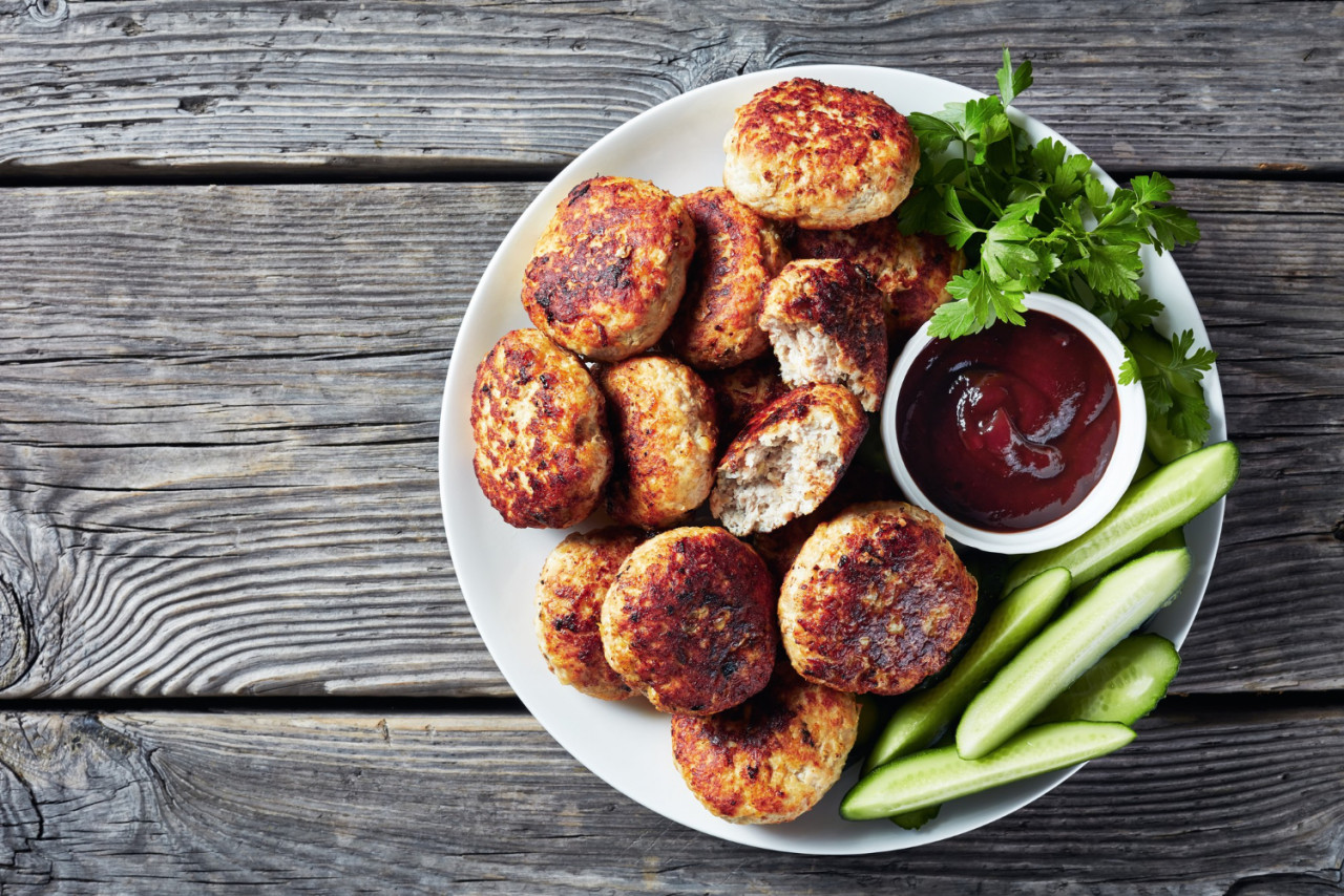 polish meat patties kotlety mielone served with cucumber barbeque sauce white plate rustic wooden table view from flatlay empty space