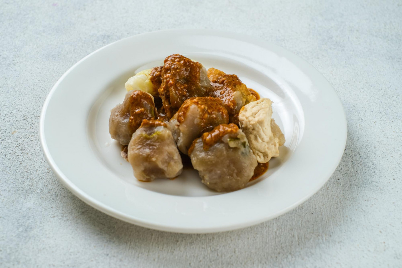 siomay bandung or steamed dumplings indonesian traditional street food with spicy peanut sauce and soy sauce served on a white plate