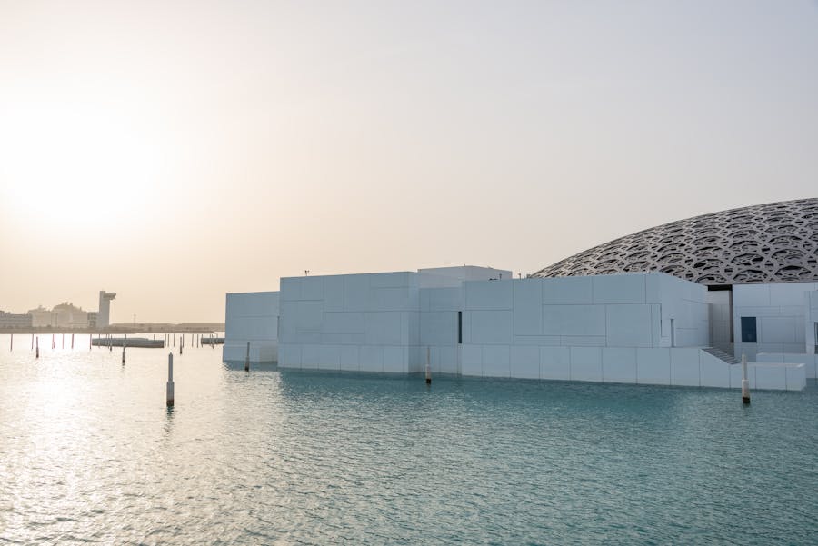 sun over water pond near futuristic building